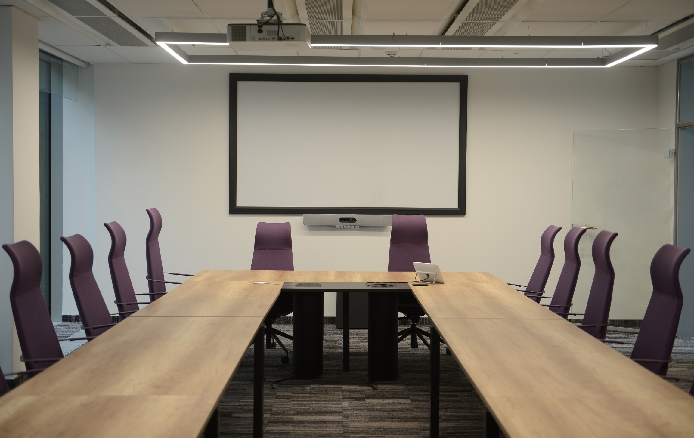 Empty office meeting room with white projector screen.